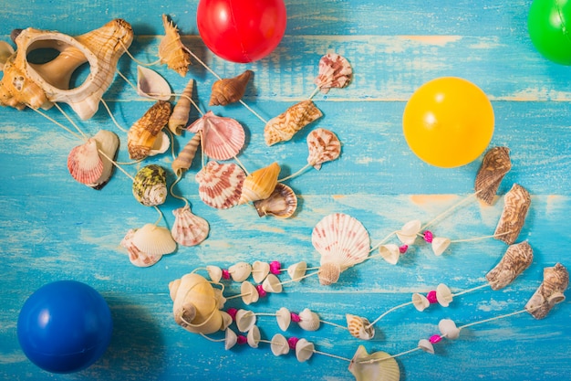 Seashells  hanging, Multiple beautiful seashells and colored balls on blue wooden table. 