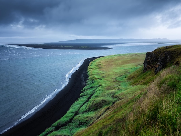 Seashore in Iceland High rocks and grass at the day time near sea Natural landscape at the summer Icelandic travel image