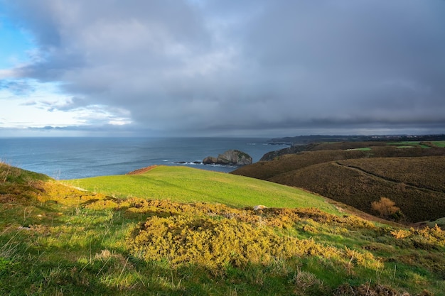 Seaside cliffs with green fields and storm clouds in the sky Asturias Spain