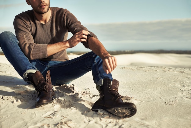 Seaside moments A man wearing jeans and boots sitting on the beach