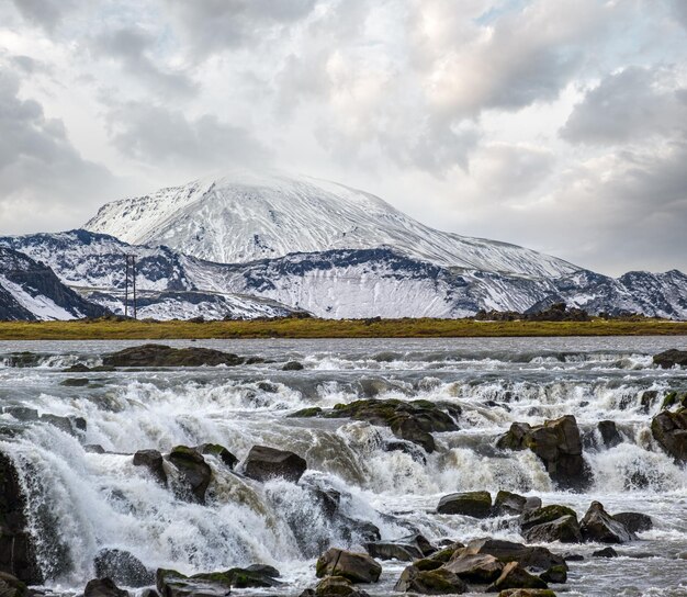 Season changing in southern Highlands of Iceland Picturesque waterfal Tungnaarfellsfoss panoramic autumn view Landmannalaugar mountains under snow cover in far