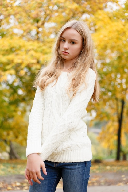 Season and people concept - beautiful happy young woman having fun with leaves in autumn park