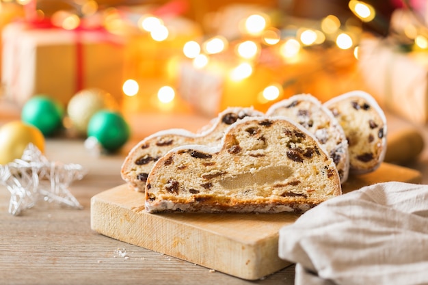 Seasonal food and drink, winter concept. Traditional European German homemade Christmas cake, pastry dessert Stollen on a wooden backgrounds with festive decoration.