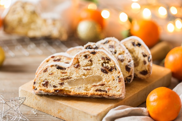 Seasonal food and drink, winter concept. Traditional European German homemade Christmas cake, pastry dessert Stollen on a wooden backgrounds with festive decoration.