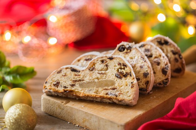 Seasonal food and drink, winter concept. Traditional European German homemade Christmas cake, pastry dessert Stollen on a wooden backgrounds with festive decoration.