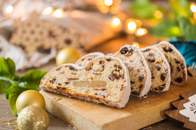 Seasonal food and drink, winter concept. Traditional European German homemade Christmas cake, pastry dessert Stollen on a wooden backgrounds with festive decoration.