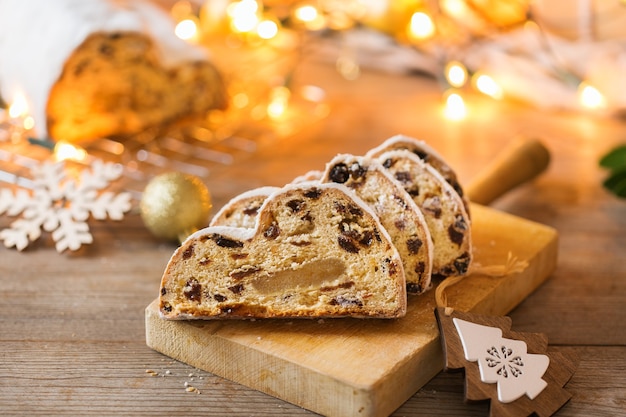 Seasonal food and drink, winter concept. Traditional European German homemade Christmas cake, pastry dessert Stollen on a wooden backgrounds with festive decoration.