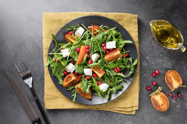 Seasonal salad with persimmon arugula cheese and pomegranate Healthy lunch plate