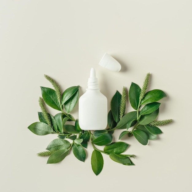 Seasonal spring allergies fresh spring blooming branches tree with green new leaves and mock up white nasal spray bottle beige background top view trend pattern Seasonal allergy concept