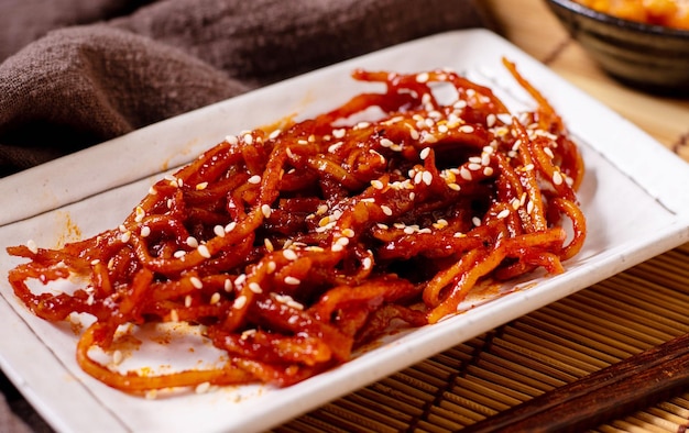 Seasoned dried shredded squid (ojingeochae muchim) with kimchi on wood table