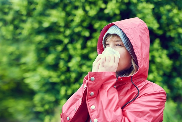 Seasons are changing and so is my health Cropped shot of a young woman blowing her nose outdoors