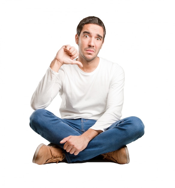 Seated young man with a loser gesture