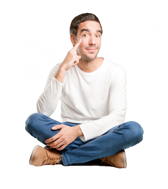 Seated young man with an observe gesture