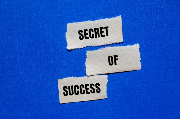 Photo secret of success message written on ripped torn paper peices with blue background conceptual secret of success symbol copy space