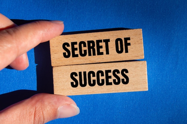 Photo secret of success message written on wooden blocks on blue background conceptual secret of success symbol copy space