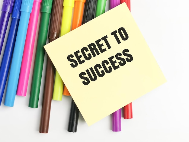 Photo secret to success written on yellow paper note with colorful pen.