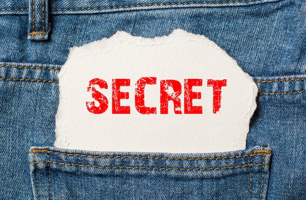 Secret on white paper in the pocket of blue denim jeans