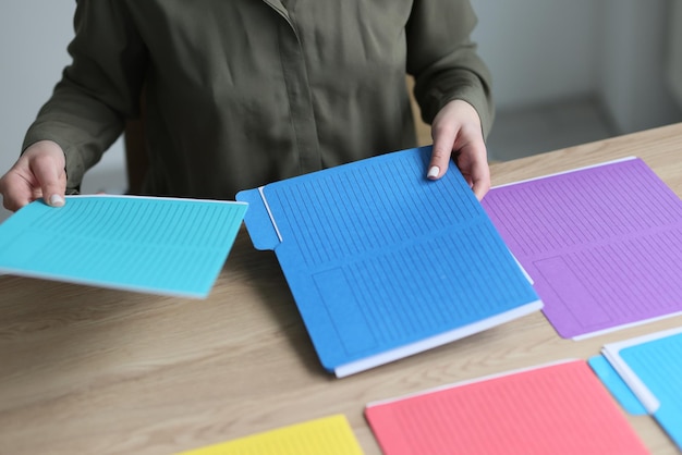 Secretary sorts colorful folders with accounting materials and documents on wooden table