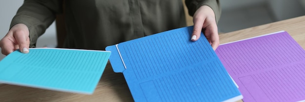 Secretary sorts colorful folders with accounting materials and documents on wooden table