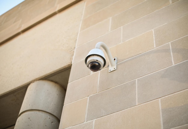 Security camera mounted on a building overlooking a busy street while roadside camera on a pole cap