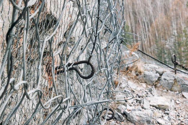 Security metal net covers the rocky cliff from falling rocks