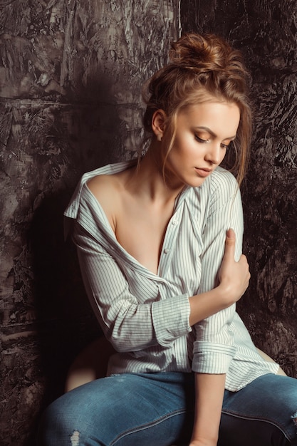 Seductive young woman sitting on a chair over a black background