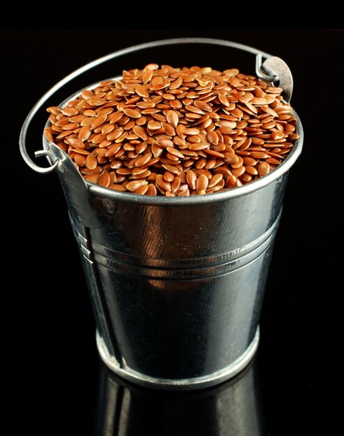 Seeds of flax in a bucket on a black surface