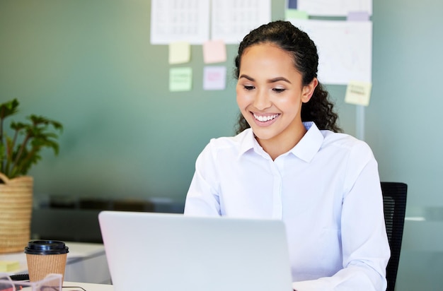 Seeing positive feedback makes me happy Shot of an attractive young businesswoman sitting alone in the office and using her laptop