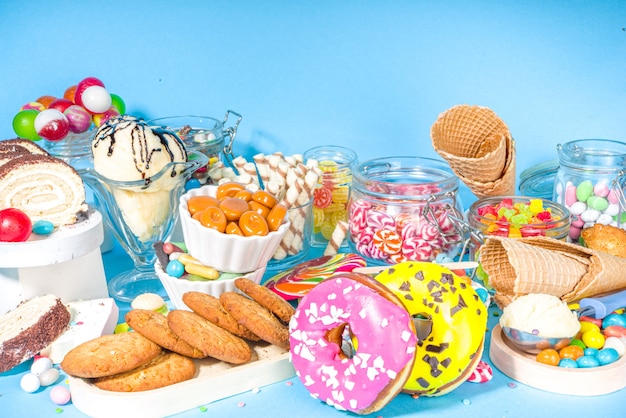 Selection of colorful sweets. Set of various candies, chocolates, donuts, cookies, lollipops, ice cream top view on trendy bright blue sunny background