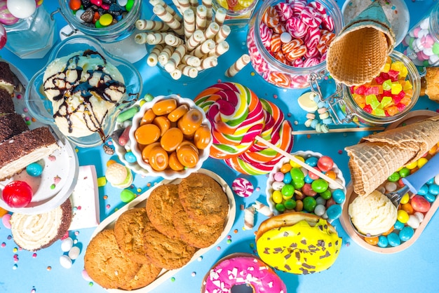 Selection of colorful sweets. Set of various candies, chocolates, donuts, cookies, lollipops, ice cream top view on trendy bright blue sunny background