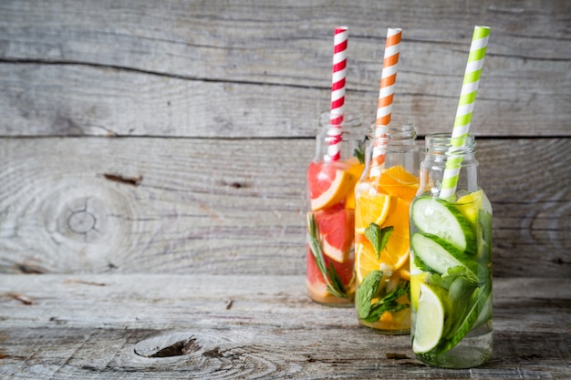 Selection of infused water in glass bottles, rustic wood background