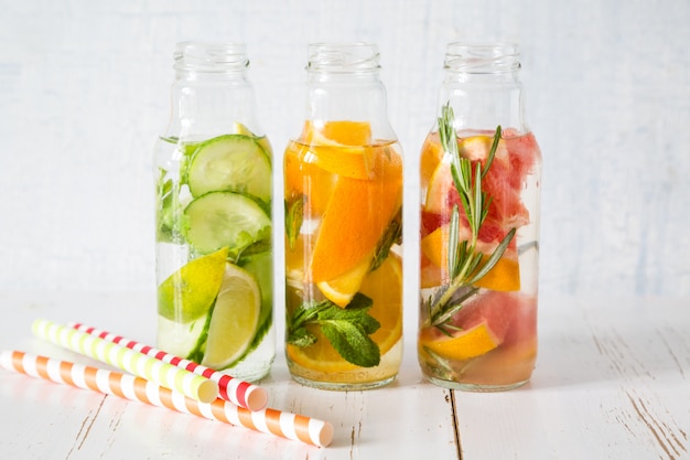 Selection of infused water in glass bottles, rustic wood background