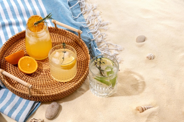 Selection of summer alcoholic cocktails on a wicker tray on beach with white sand Summer sea vacation and travel concept Exotic summer drinks