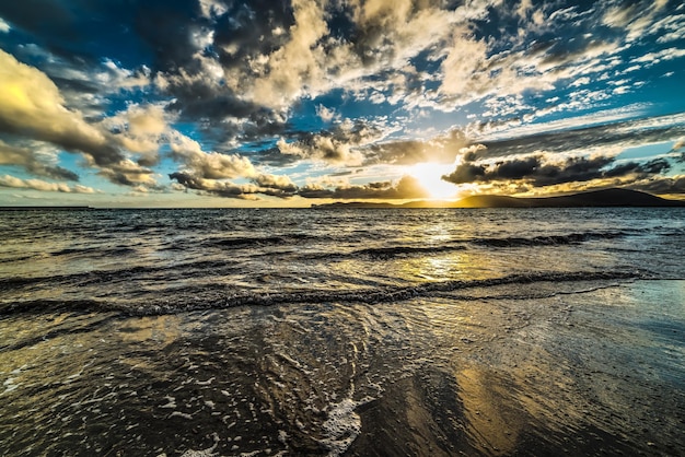 Selective desaturation of a dramatic sky over the sea at sunset