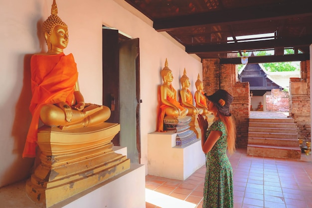 Selective focus on buddha statue young woman praying at temple in Ayutthaya Thailand