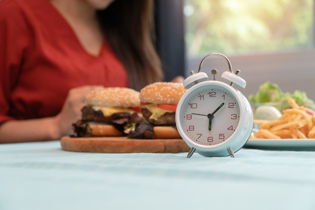 Selective focus of clock, Young woman ready to eating Breakfast