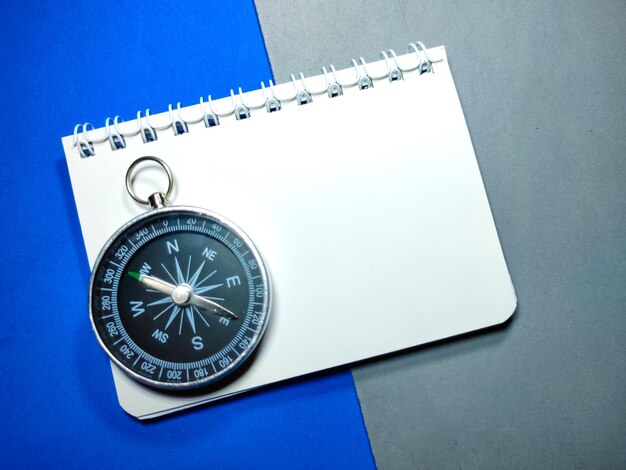 Selective focus of compass and notebook on gray and blue background with copy space