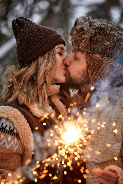 Selective focus Couple Love Story in Snow Forest Kissing and Holding Sparklers Couple in Winter Nature Couple Celebrating Valentine's day date