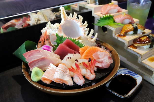 Selective focus decorated sashimi set in a bowl with ice and conch shell another sushi set behind