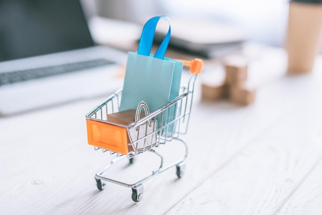 Selective focus of decorative package and shopping bag in cart on wooden desk