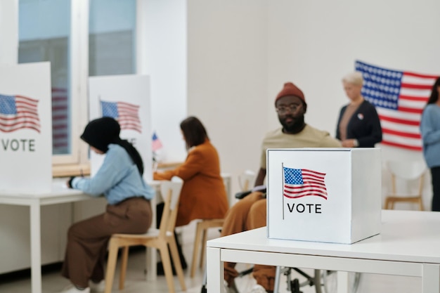 Selective focus on desk with ballot box for papers with chosen candidates