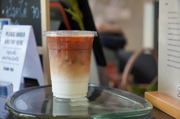 Selective focus Fresh coffee iced cappuccino Macchiato latte with two tones layer separate milk and coffee cold Iced black coffee mixed with milk in plastic glass on wooden table in cafe