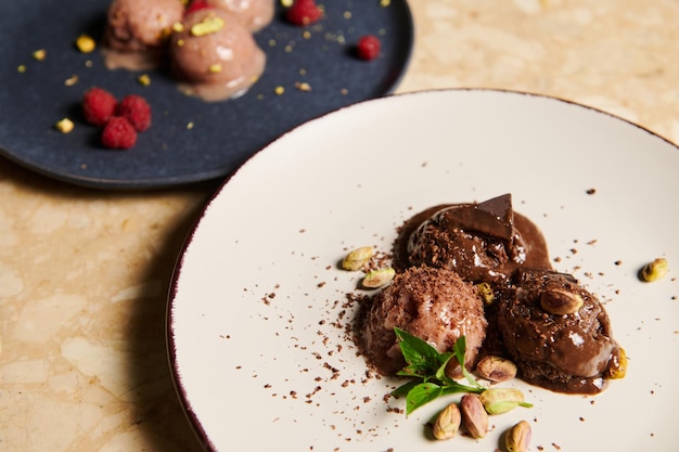 Selective focus on frozen balls of chocolate pistachio ice cream with partial view of raspberry sorbet on the background