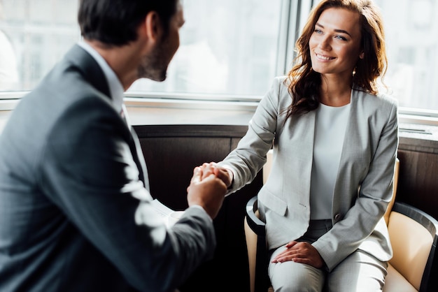 Selective focus of happy businesswoman shaking hands with businessman