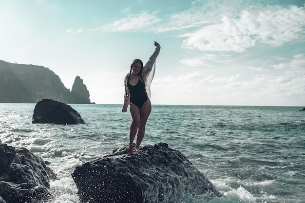 Selective focus Happy carefree sensual woman with long hair in black swimwear posing at sunset beach Silhouette of young beautiful playful positive woman outdoor Summer vacation and trip concept