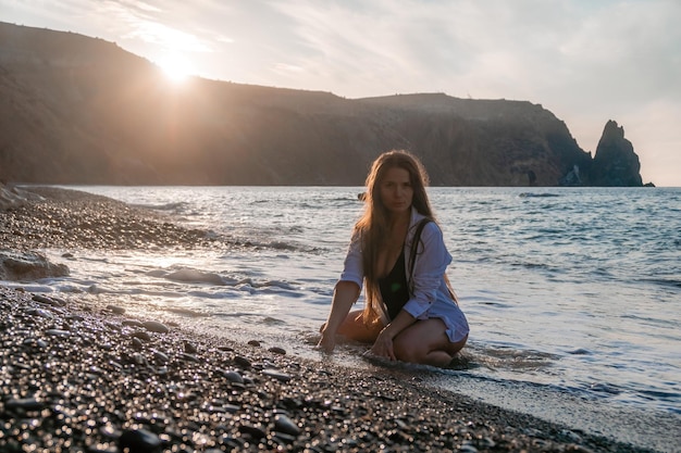 Selective focus happy carefree sensual woman with long hair in black swimwear posing at sunset beach