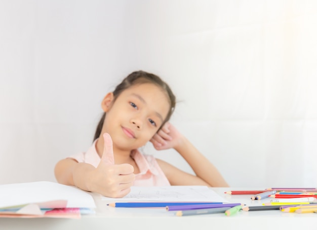 Selective focus of Happy little girl kid giving thumb up as sign of success, Kid drawing concept