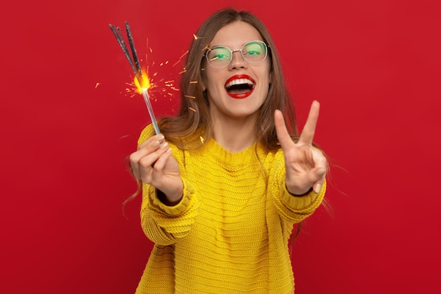 selective focus of happy Woman holding sparklers and showing peace sign