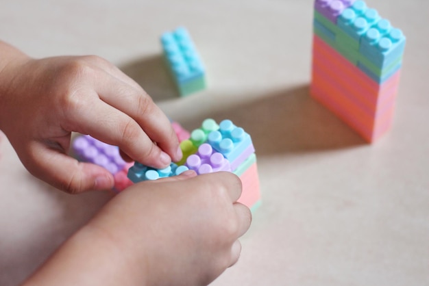 Selective focus image of child's hands playing with colorful plastic blocks Copy space for text