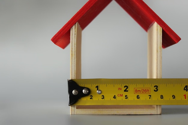 Photo selective focus image of miniature house and measuring tape with copy space house renovation concept